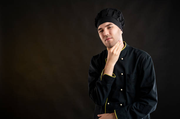 istock Young male dressed in a black chef suit has sore throat 1276587602