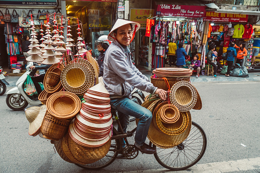 HANOI, VIETNAM - DECEMBER 14, 2018 : Street scene of the Old Quarter of Hanoi. Street vendor selling various types of traditional vietnamese hats from the bicycle