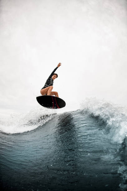 istock athletic woman effectively jumps with surf board on the wave 1276594009