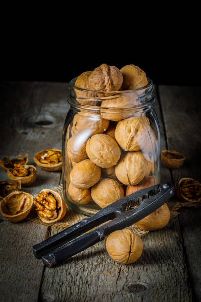 bodegones con nueces y cascanueces sobre fondo de madera. imagen vertical. enfoque selectivo - nuez fotografías e imágenes de stock