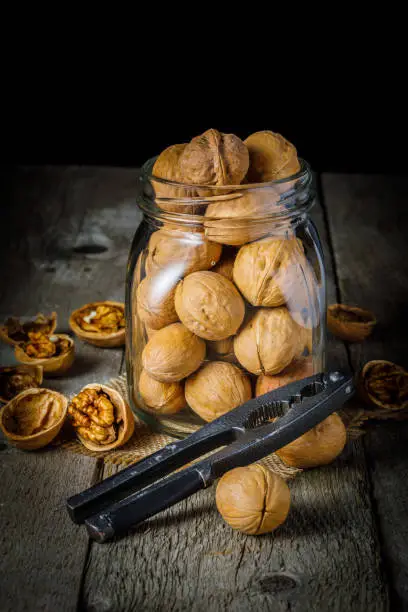 still life with walnuts and nutcracker on wooden background. Vertical image. Selective focus