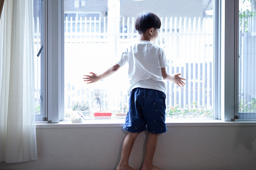Boy looking out from the window of the house