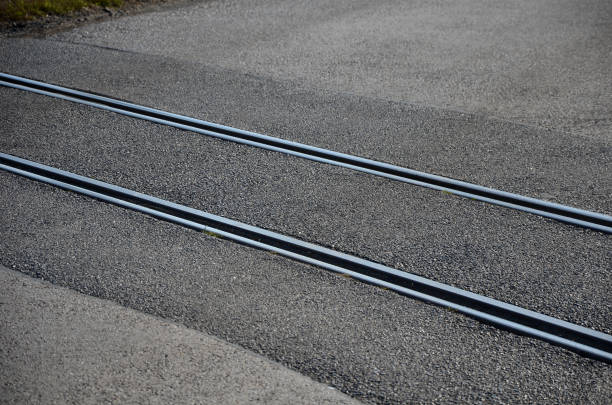 train, tracks, leading, across, asphalt, road, crossing, obliqueiy, direction, travel, risk, single, track, vehicle, vehicles, event, icing, wet, rain, weather, skidding, bicycles, motorcycles, danger, dangerous, ride, slowly, accident, crash, car, bike, lawn, meadow, gray, street, diagonally, intersection, junction, crossroads, railway, railroad, rail, transportation, transport vías del tren que conducen a través de la carretera de asfalto oblicuamente a la dirección de viaje. existe el riesgo de un accidente de vehículos de una sola vía en caso de hielo o clima húmedo. el riesgo de derrapar es posible con bicicletas y moto