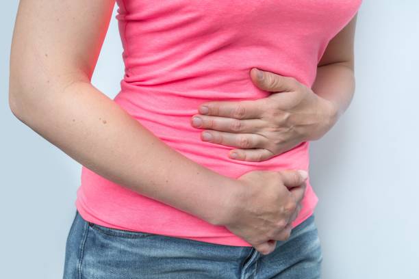 istock Woman with menstrual pain is holding her aching belly 1276601355