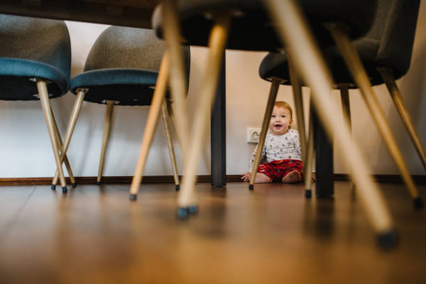 istock Adorable baby boy crawling underneath table. Real life toddler infant crawls under table at living-room or kitchen. Beautiful kid under the table. 1276603254