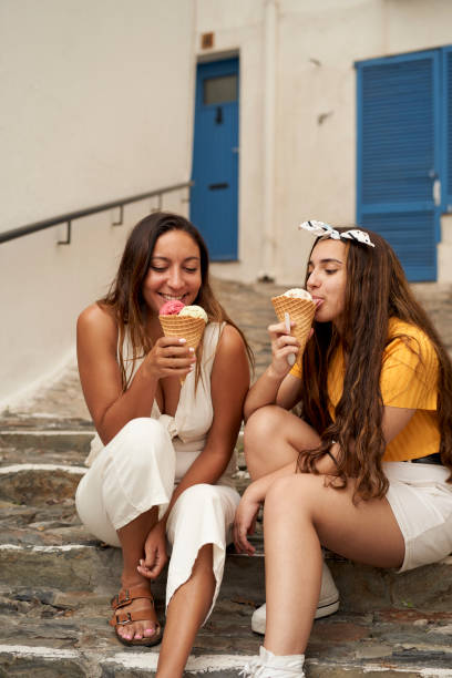 istock Two sisters having ice cream together outdoors. 1276605784