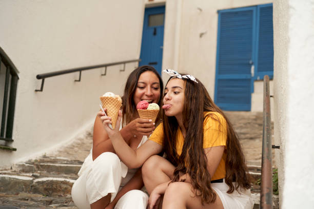 istock Two sisters having ice cream together outdoors. 1276605829