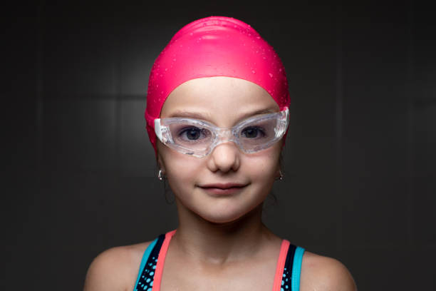Closeup portrait of a little smiling swimmer girl with dark background.