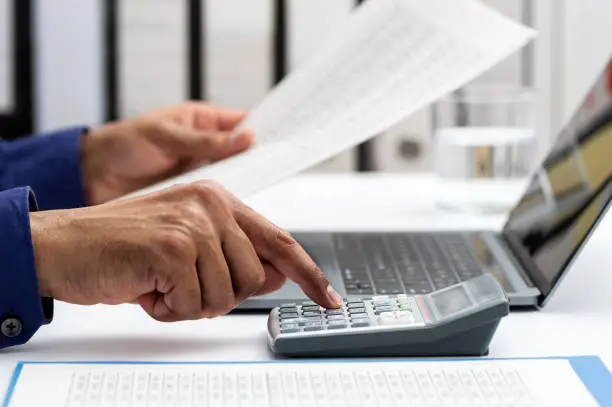 Photo of businessman accountant calculating with a calculator