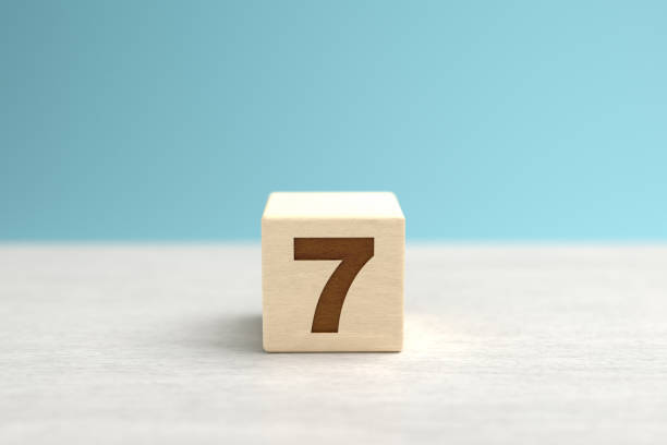 A wooden toy cube with the number 7. stock photo