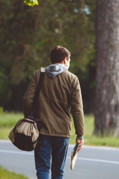 istock Man with map and bag in hand walking on a roadside 1276613051