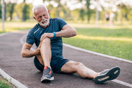 Senior man runner with knee pain in the park