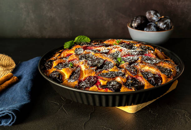 Homemade plum pie with cinnamon. Fruit tart on black table.