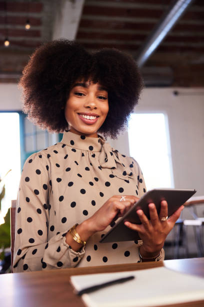 istock Smiling young businesswoman sitting at a table using a digital tablet 1276616278