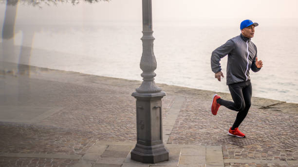 homme adulte moyen courant sur le sentier dans le matin brumeux - distance running jogging running fog photos et images de collection