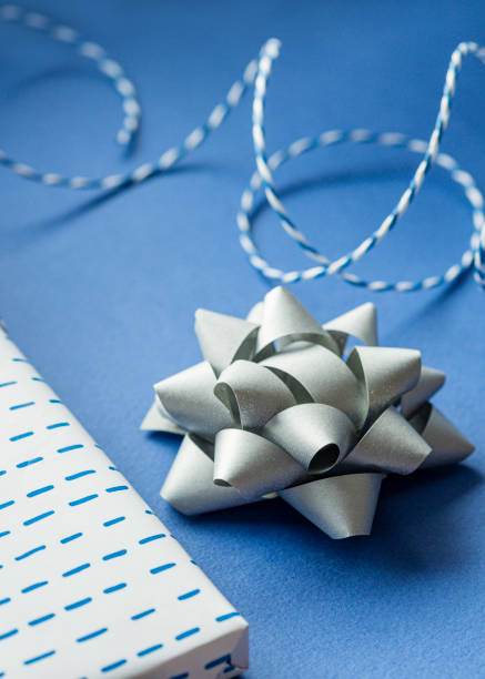 istock Gift packaging: silver bows for gift decoration, blue gift rope, gift in a white box on a blue background. Preparing for Christmas holidays. Selective focus 1276616497