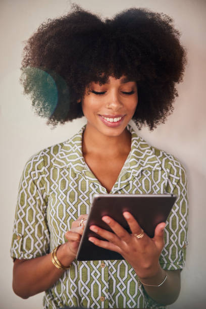 istock Young African American woman smiling while using a digital tablet 1276616845