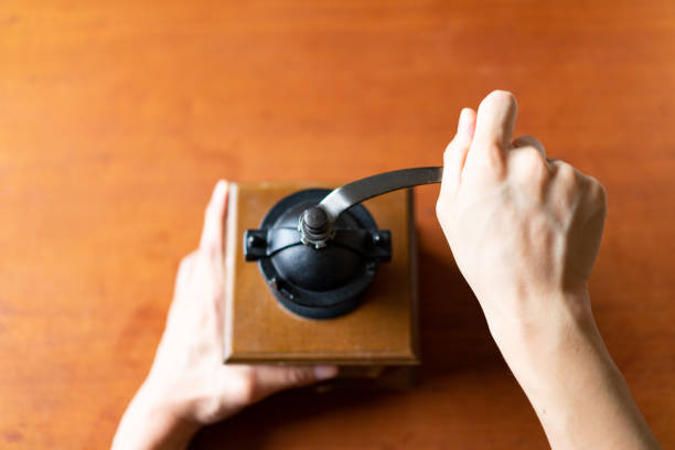 Brewing Coffee at Home - Grind coffee beans.Hand-crank coffee mill.Taken in natural light. Wooden table.