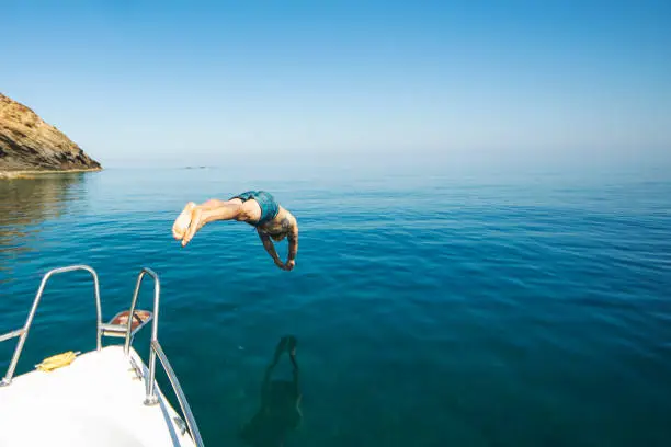 Photo of Young adult man diving from his yacht