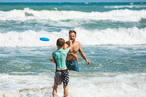Father and son playing frisbee at the beach