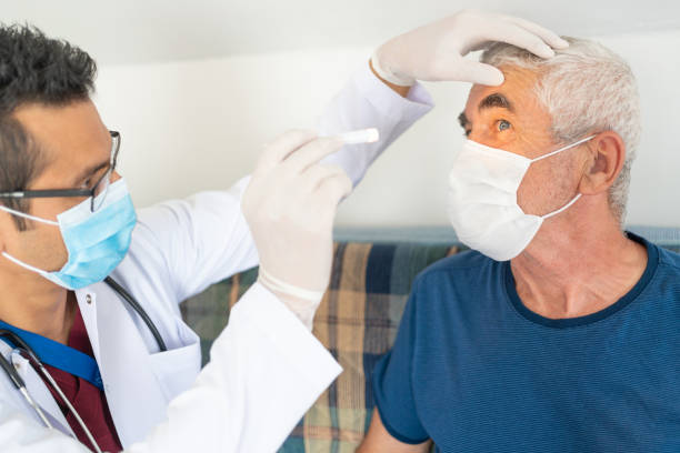 un agent de santé examine les yeux d’un homme âgé dans sa maison pendant l’épidémie de coronavirus - scrubs professional sport indoors healthcare and medicine photos et images de collection