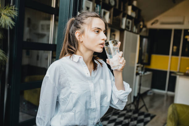 istock Young woman drinking water at home 1276619524