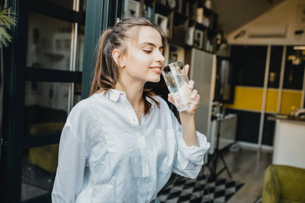 istock Young woman drinking water at home 1276619546