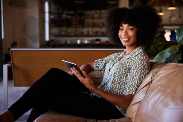 istock Smiling young woman sitting on a sofa and using a digital tablet 1276620374