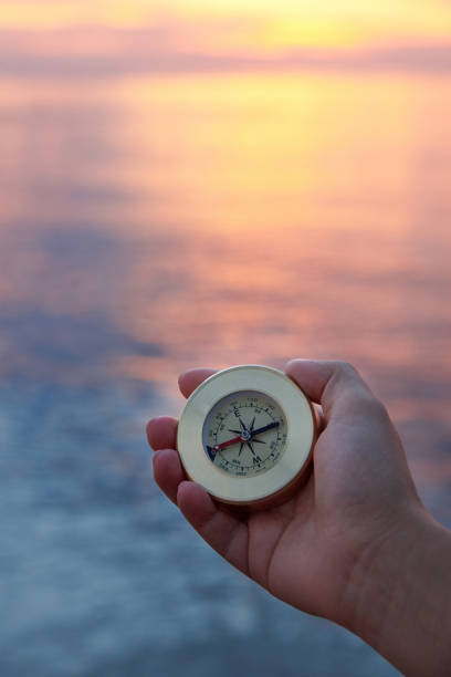 ręka kobiety z kompasem na wybrzeżu morskim o wschodzie słońca. - compass exploration the way forward beach zdjęcia i obrazy z banku zdjęć