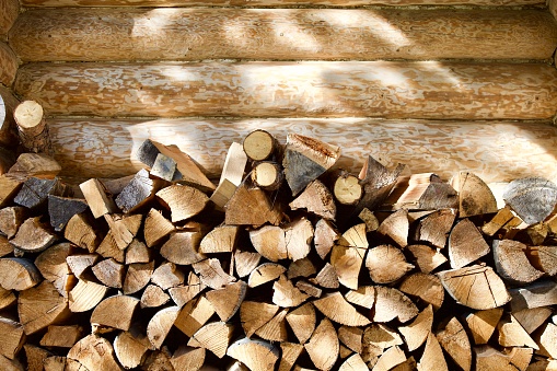 Stacked firewood near the wall of a log village house close-up