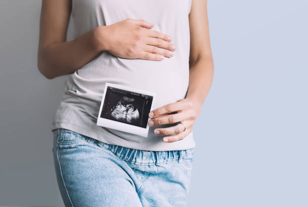 těhotná žena drží ultrazvukový obraz dítěte. detail těhotné břicho a sonogram fotografie v rukou matky. - nemocnice fotky - stock snímky, obrázky a fotky