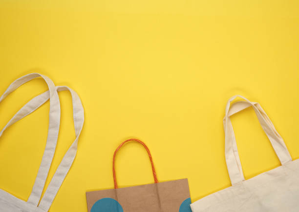 istock paper and empty beige textile bag on yellow background 1276623172