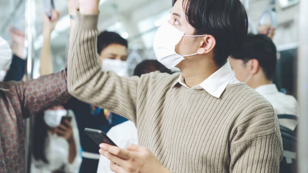 istock Traveler wearing face mask while using mobile phone on public train 1276625302