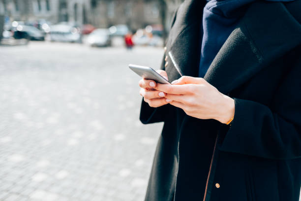 istock Woman wearing black coat using smart phone 1276628241