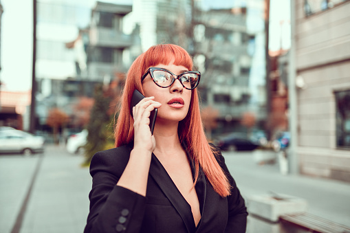 Elegant Businesswoman Talking On Phone While Walking In City Center