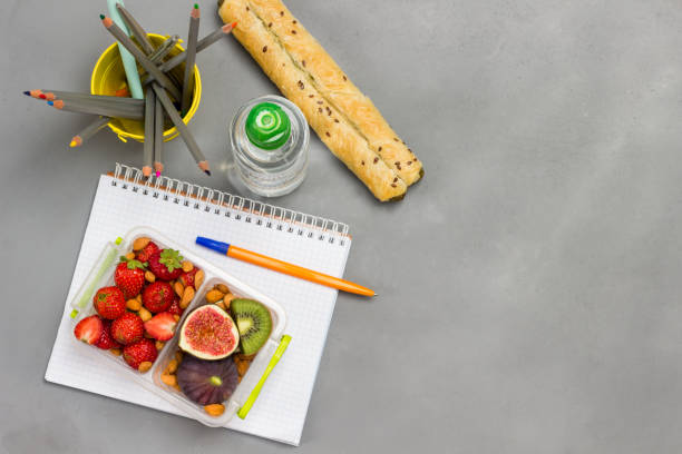 pożywne pudełko na lunch z owocami, jagodami i orzechami na otwartym notatniku. - strawberry plant audio zdjęcia i obrazy z banku zdjęć