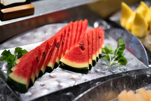 Fresh watermelon pieces which is served in the metal plate at breakfast buffet line. Close-up and selective focus at enter part.