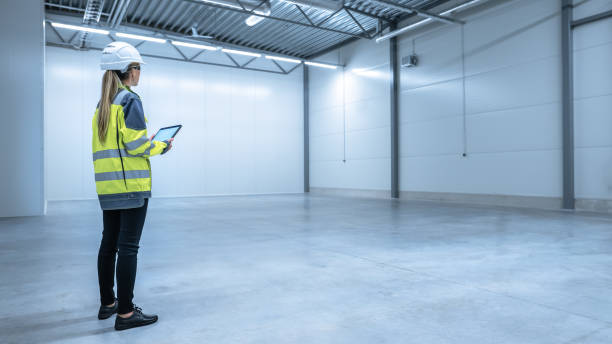 istock Industry 4.0 Modern Warehouse: Female Engineer in Empty Warehouse Uses Digital Tablet Computer with Augmented Reality Software for Future Factory or Warehouse Layout. Concept Shot of Augmented Reality 1276633085