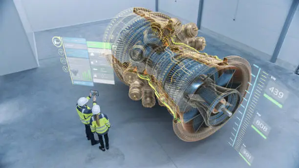 Photo of Industry 4.0 Two Engineers Standing and Talking in Factory Workshop with Augmented Reality 3D Model Concept of Giant Turbine Engine. Graphics Visualization. High Angle Shot. VFX Special Visual Effects