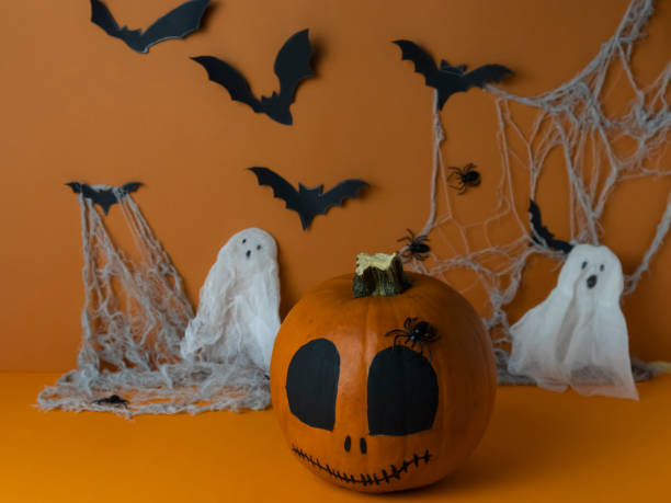 orange pumpkin for halloween on the background of old cobwebs, bats and spiders, halloween party concept orange pumpkin for halloween on the background of old cobwebs, bats and spiders, halloween party concept halloween pumpkin human face candlelight stock pictures, royalty-free photos & images