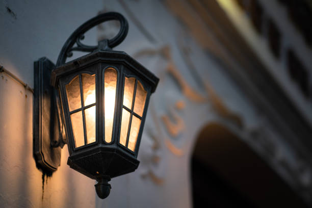 A classic lighting lamp during it turning-on the orange warm-light, with blurred background of European style architecture building. Close-up object photo.