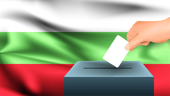 Male hand puts down a white sheet of paper with a mark as a symbol of a ballot paper against the background of the Bulgaria flag. Bulgaria the symbol of elections