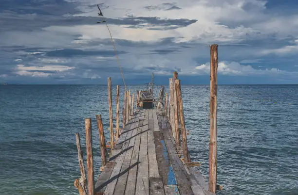 Photo of Wooden bridge and the sea with dark rain cloudy.