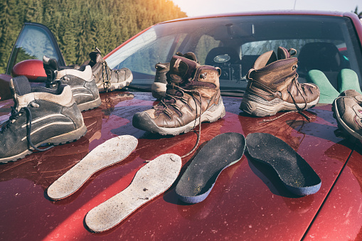 a lot hiking boots close-up stand on the roof of the car after tracking and beautiful mountain landscape\