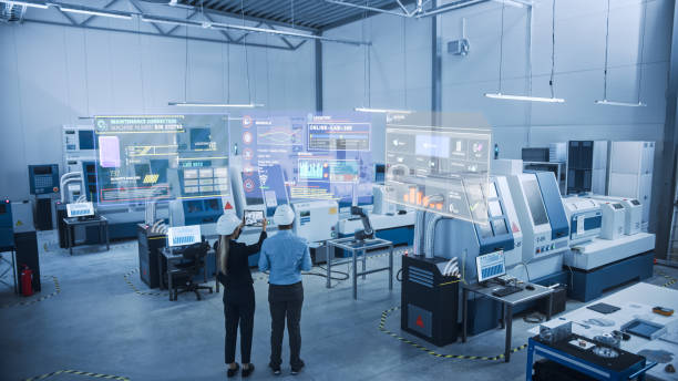 산업 4.0 공장: 두 명의 엔지니어가 증강 현실 소프트웨어가 있는 디지털 태블릿 컴퓨터를 사용하여 첨단 기계, 로봇 암 및 장비의 유지 보수 및 진단을 시각화합니다. - 산업 이미지 뉴스 사진 이미지
