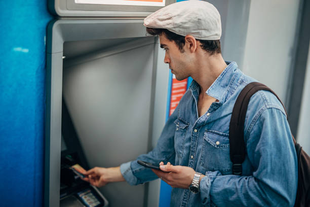 istock Handsome man withdrawing money from ATM 1276638488