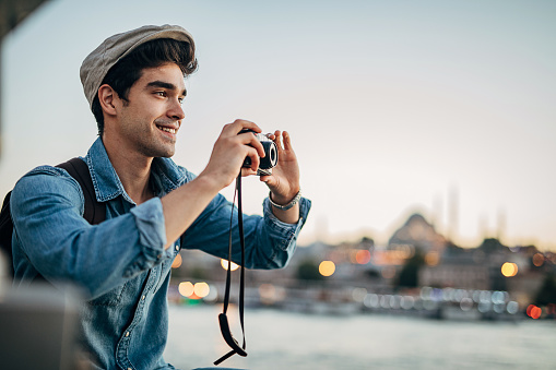 Young handsome caucasian male tourist taking photos with camera.