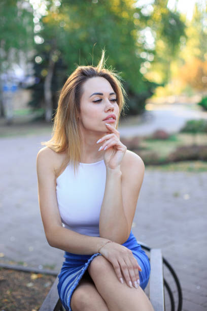 istock Young beautiful woman sitting on a bench 1276639388