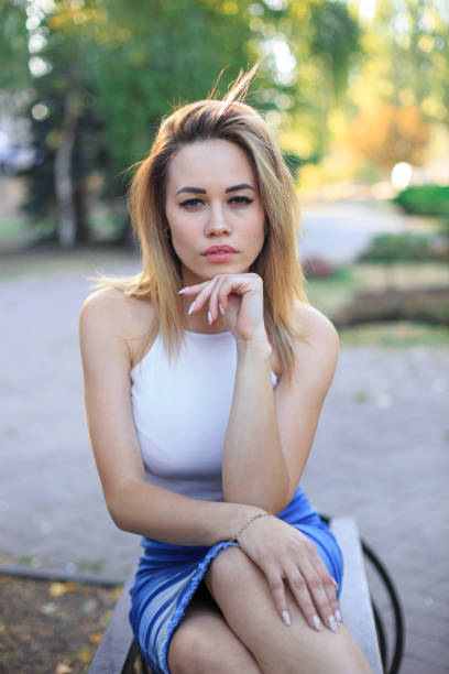 istock Young beautiful woman sitting on a bench 1276639403