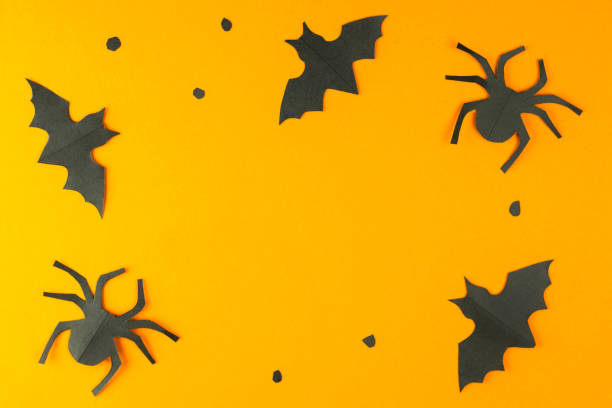 istock Black bats and spiders silhouettes made from paper on orange background. Flat lay, top view with copy space. Happy Halloween concept. Holiday frame. Handmade decoration, DIY. 1276641009